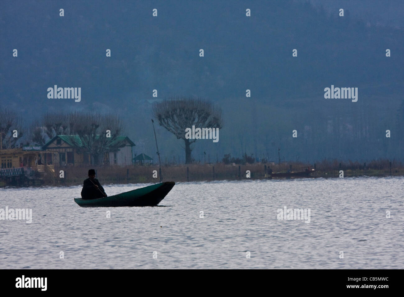 Un boatman se trouve dans le lac Dal de Srinagar, au Cachemire, en Inde, avec de l'eau calme et un paysage frais. Banque D'Images