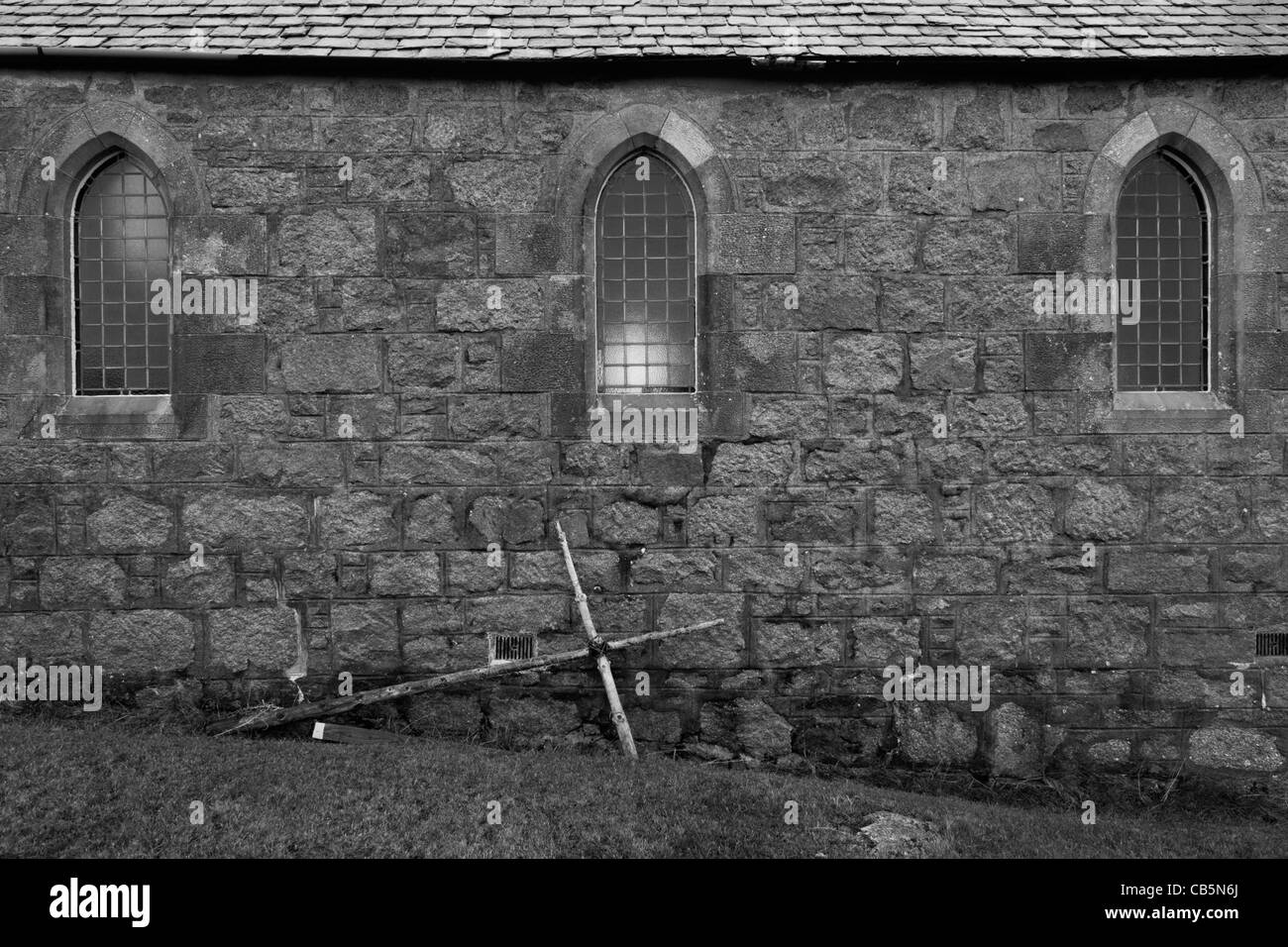 Croix Crucifix prop appuyé contre mur extérieur de l'église St Ernan, Fionnphort, Ile de Mull, en Ecosse. Banque D'Images