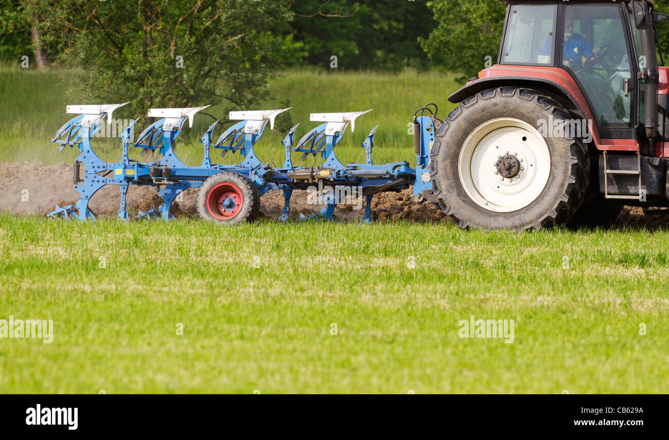 Tracteur avec charrue labourant un champ couvert d'herbe pour  l'agriculture, concept business Photo Stock - Alamy