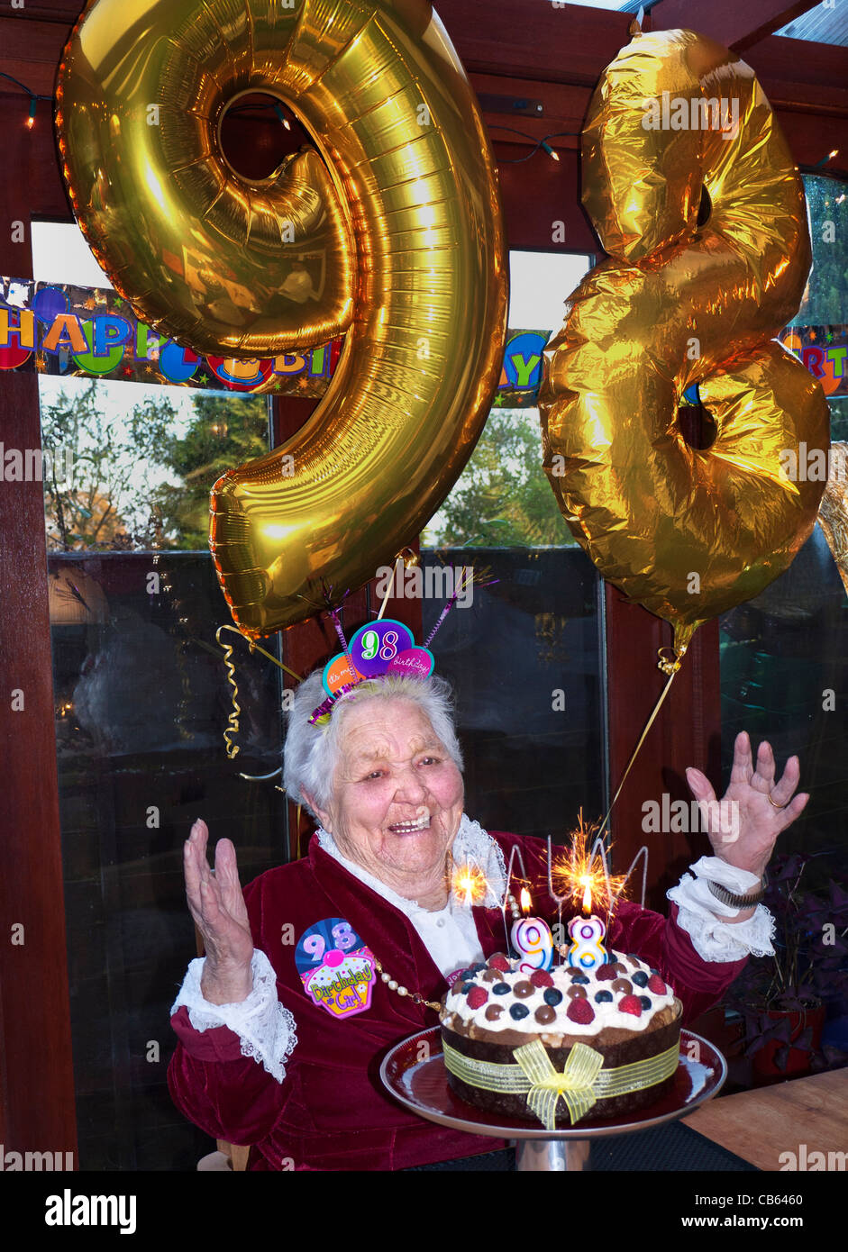 Gâteau d'anniversaire surprise âgées BALOONS alerte heureux vieille dame fête son 98e anniversaire à la maison avec la famille private clinic Banque D'Images