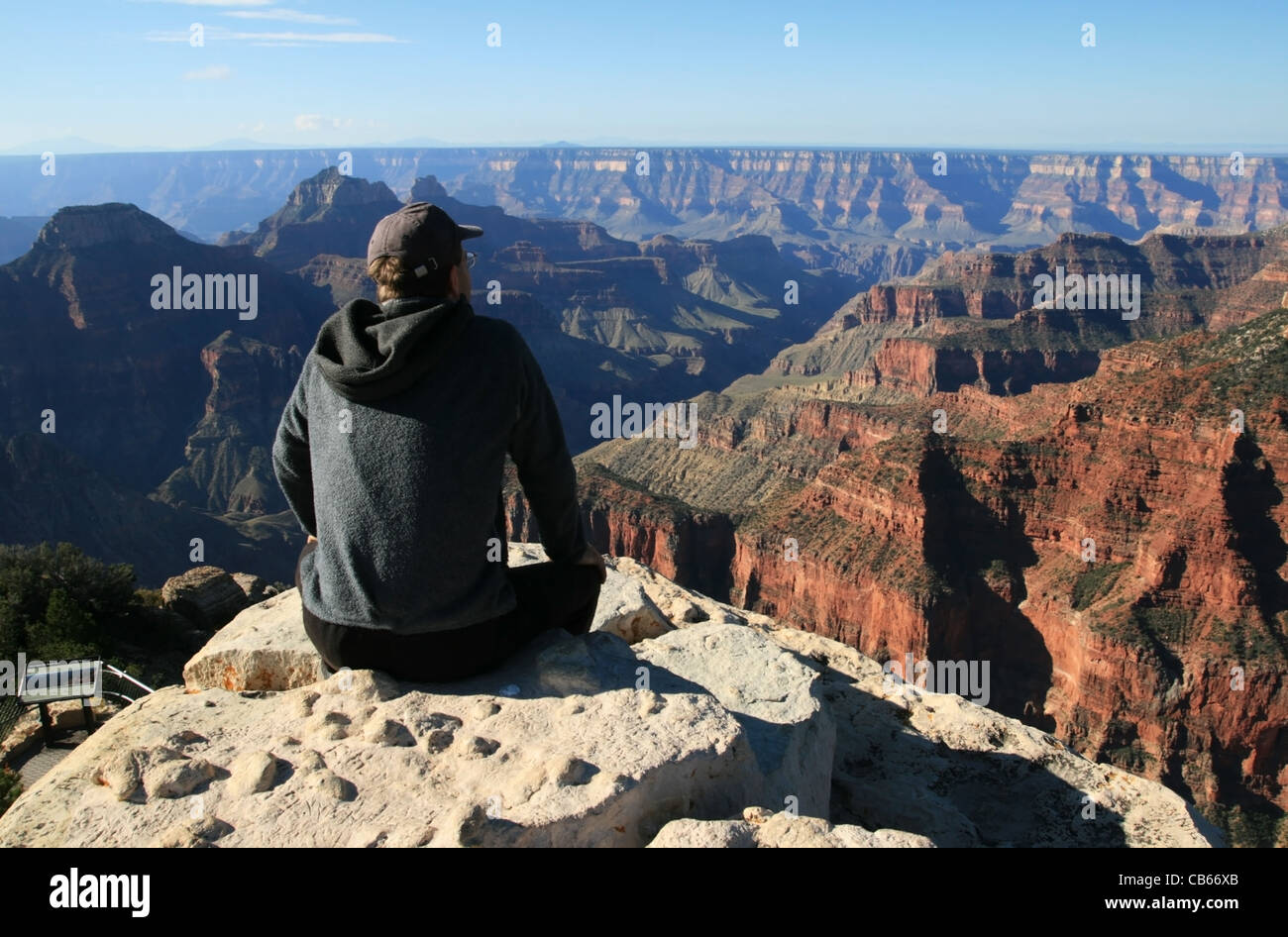 Un homme assis sur un rebord à Bright Angel point donne sur la North Rim du Grand Canyon, Arizona Banque D'Images