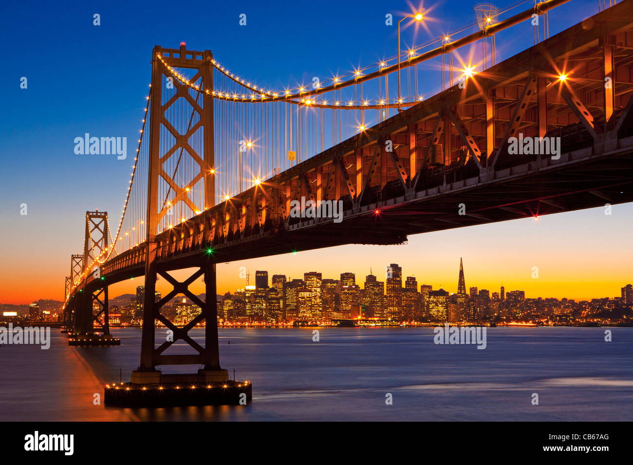 Coucher de soleil derrière l'horizon de San Francisco, sous le San Francisco Oakland Bay Bridge. Banque D'Images