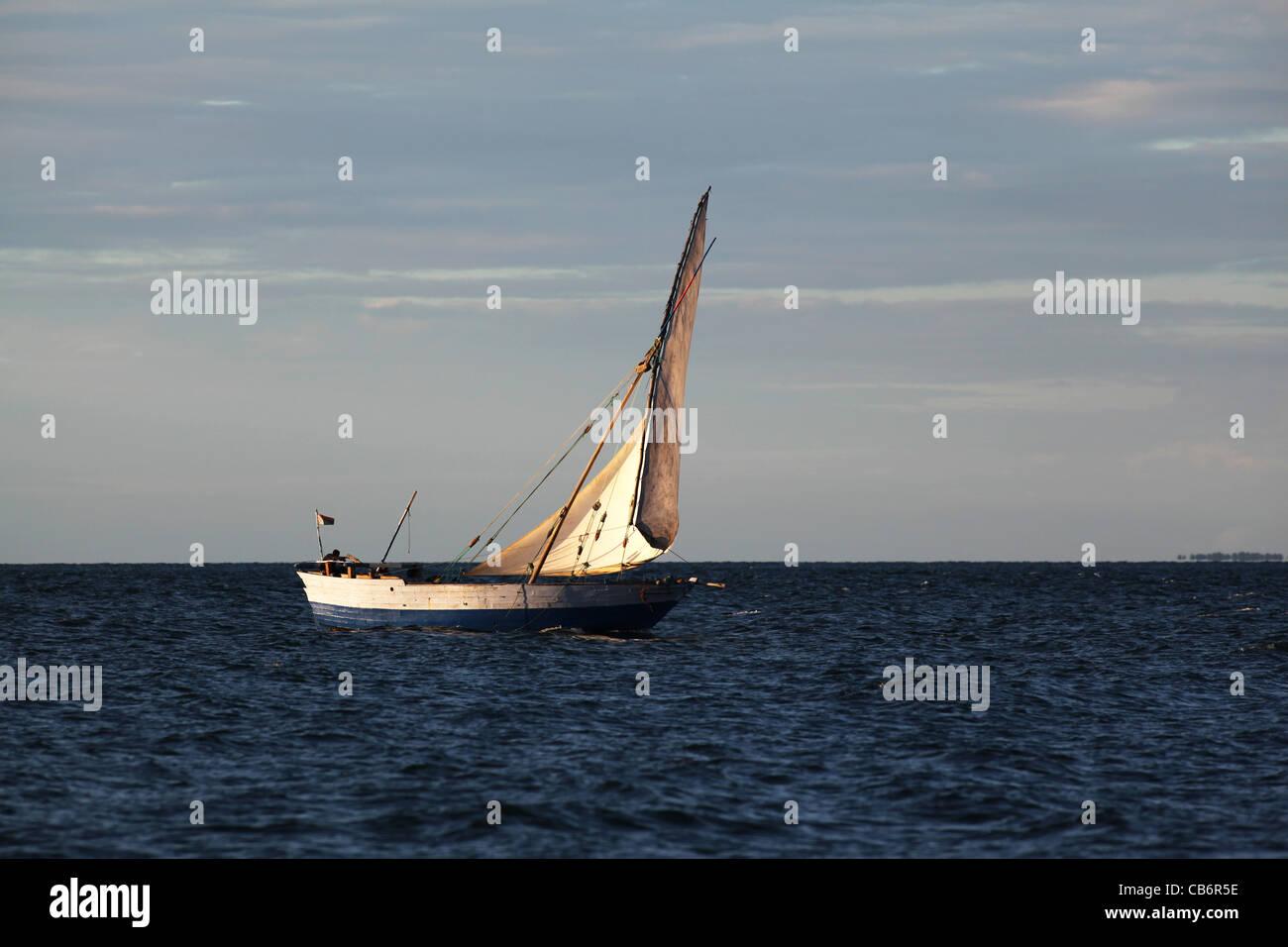 Une embarcation traditionnelle malgache, ou boutre, navigation avec un voile intégral au coucher du soleil, près de off Ankify Nosy Be, au nord-ouest de Madagascar Banque D'Images