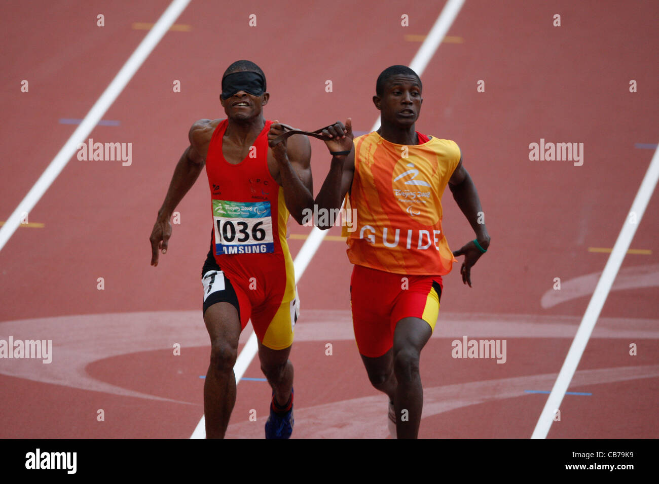 La compétition sportive aux Jeux paralympiques de 2008 montrant la finition runner angolais course pour les athlètes aveugles avec guide Banque D'Images