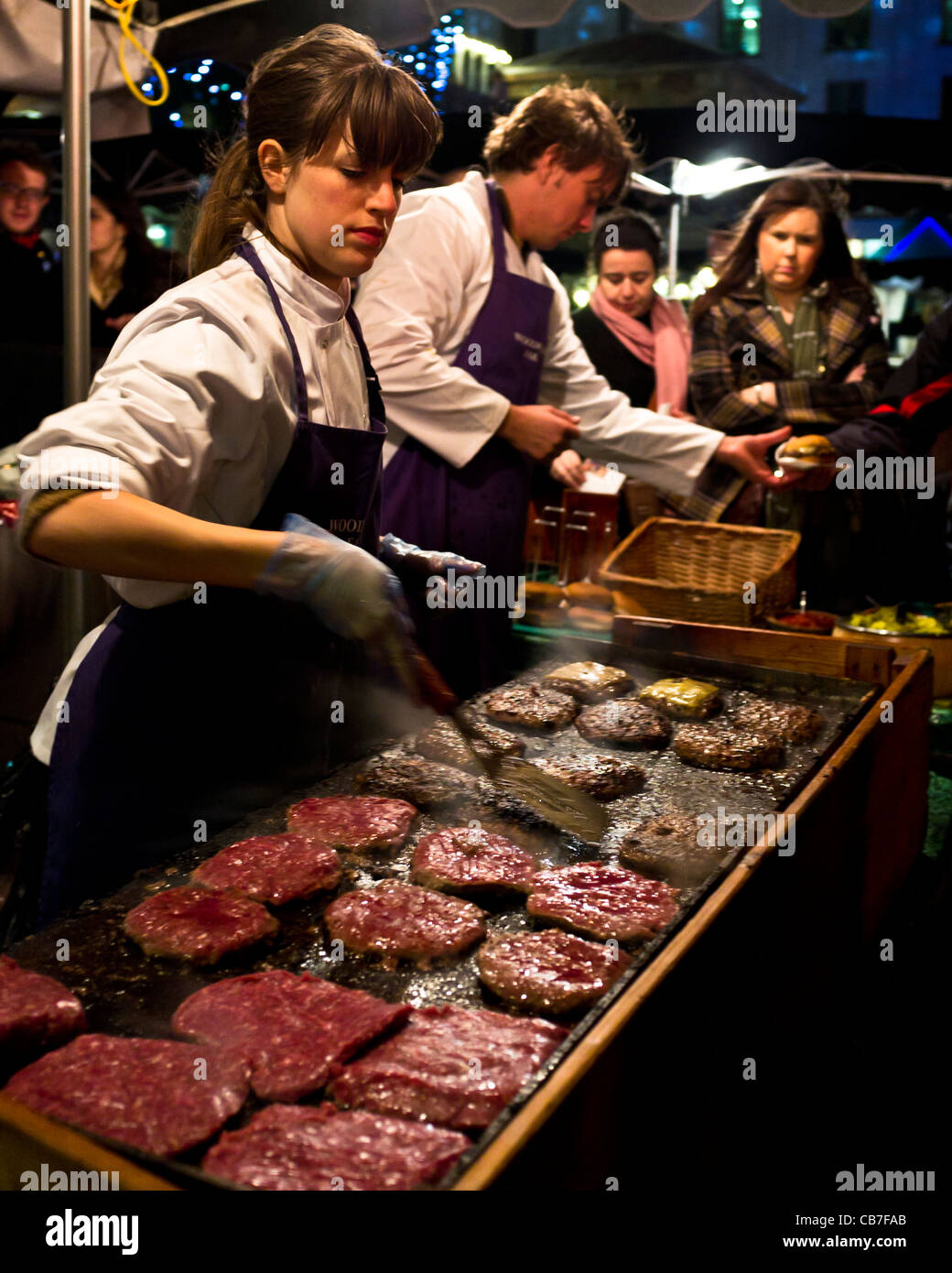 Une jeune femme se retourne sur un burger burgers en dehors de décrochage à Covent Garden à l'approche de Noël. Banque D'Images