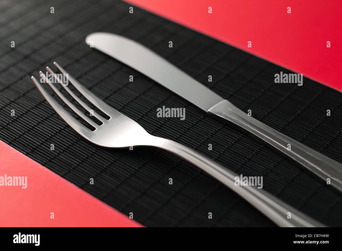 Couteau et fourchette sur le tableau noir sur des serviettes de table rouge par les côtés de la coutellerie Banque D'Images