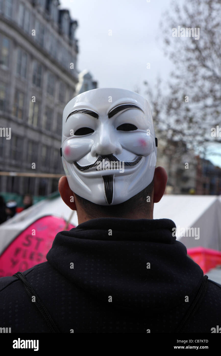 Retour de l'homme avec masque de Guy Fawkes, symbole de mouvement anonyme groupe hacktiviste anarchiste, Occupy London, la Cathédrale St Paul. Banque D'Images