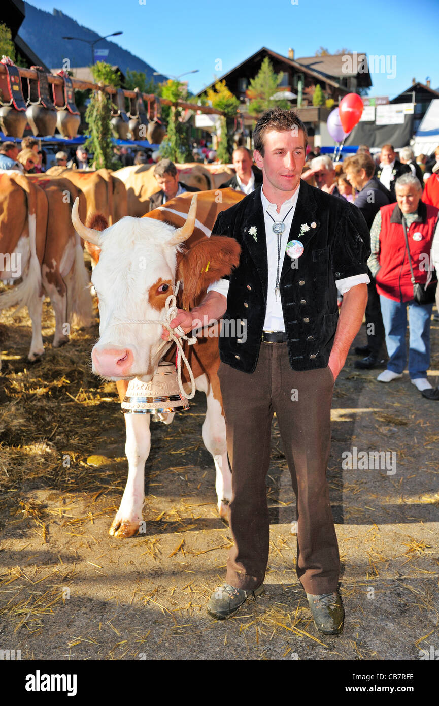 Un agriculteur suisse en costume traditionnel, avec sa vache Simmental primés. Banque D'Images