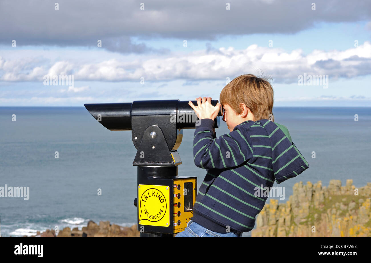 Un jeune garçon à l'aide d'un télescope à Lands End en Cornouailles, Royaume-Uni Banque D'Images