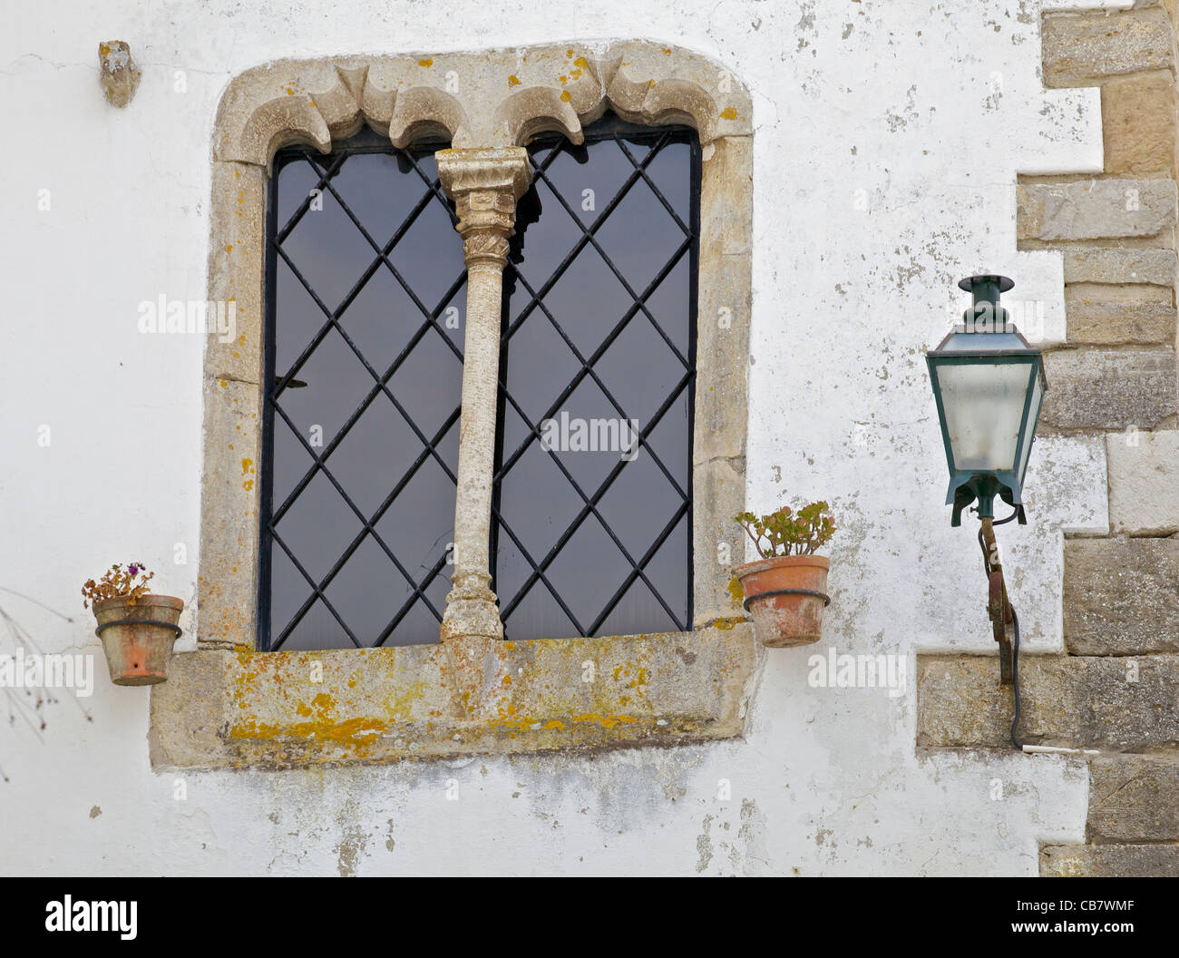 Fenêtre en pierre ouvragée détaillées à côté d'une lanterne de rue dans le village médiéval d'Obidos Banque D'Images