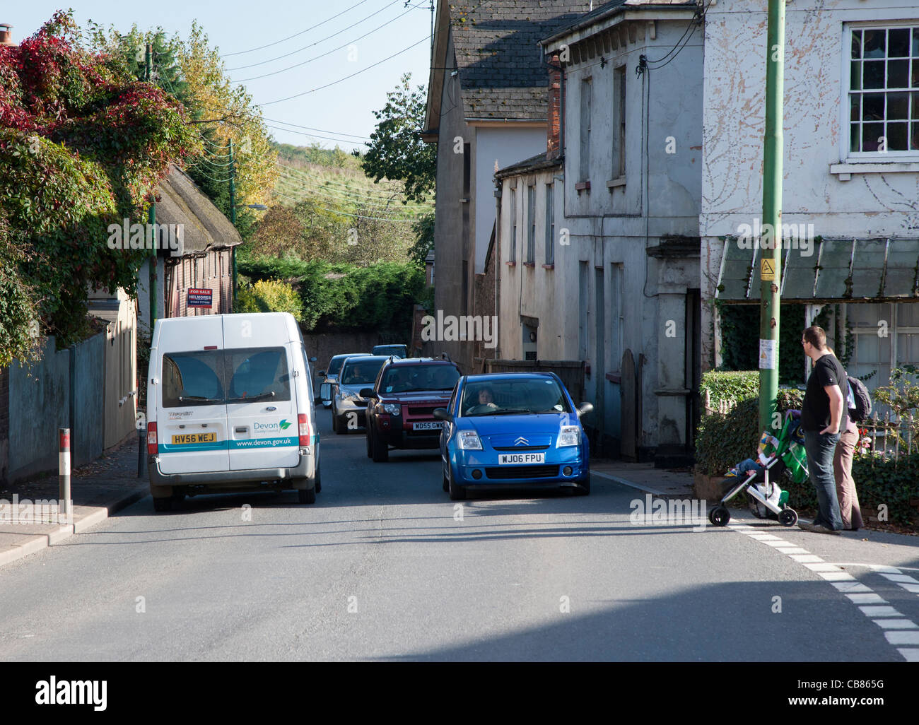 Couple avec bébé qui essaient de traverser route occupée à Crediton, Devon, Angleterre Banque D'Images