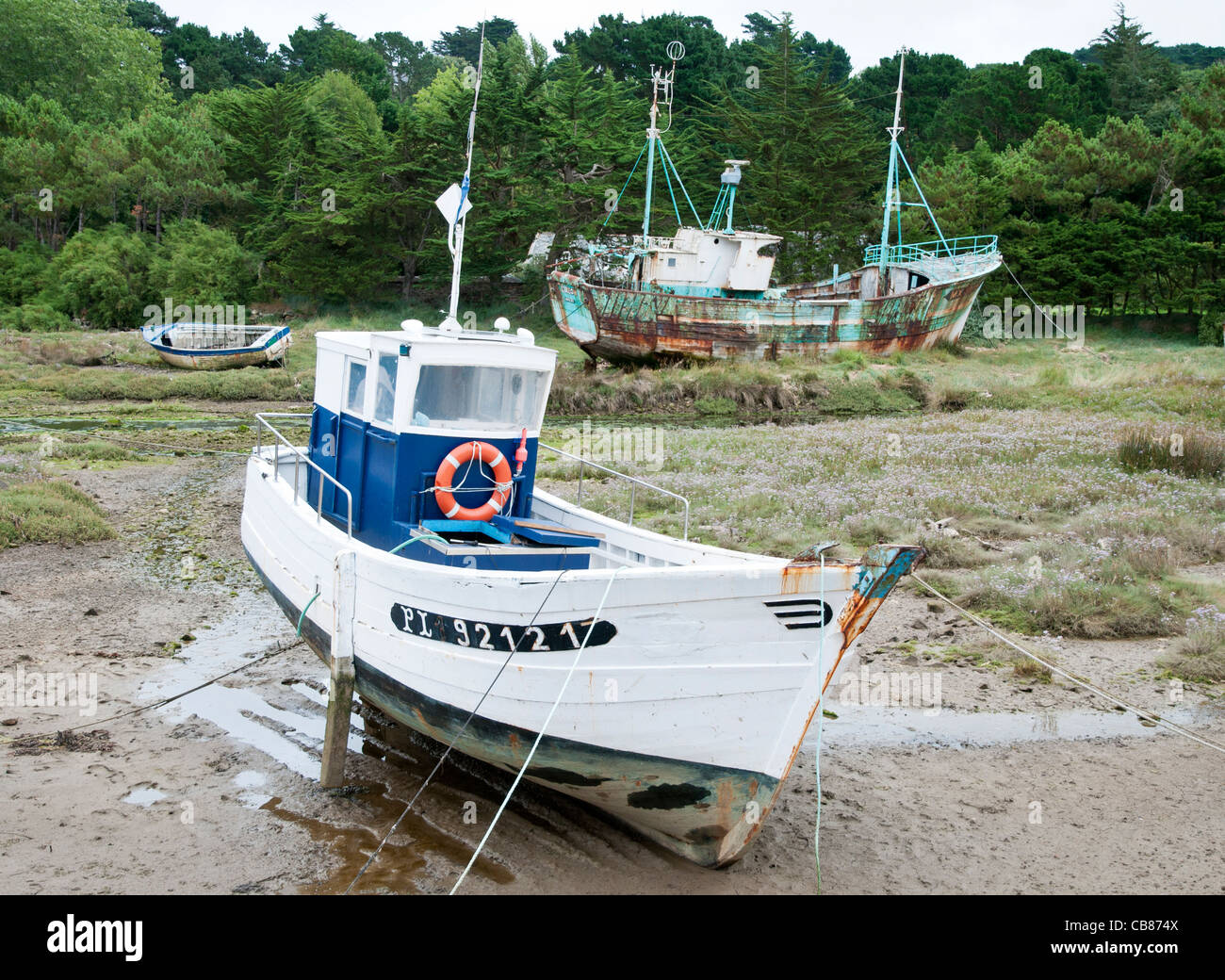 'Utilisés et non utilisés' deux bateaux de pêche à marée basse dans la baie de Morlaix, Bretagne France Banque D'Images