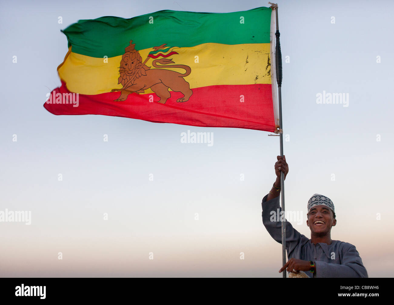 Teenage Boy brandissant le drapeau de l'Éthiopie, Lion Rastafari, tandis qu'il sourit à la caméra, Lamu, Kenya Banque D'Images