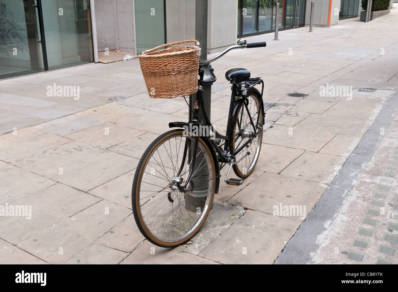 Vélo traditionnel avec un panier en osier appuyé contre un lampadaire Banque D'Images