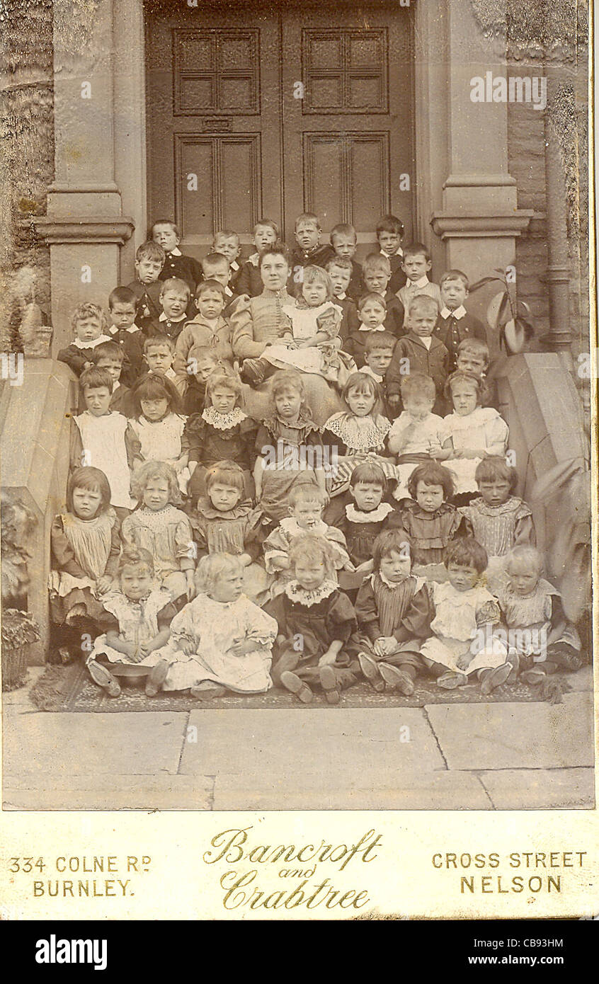 Photographie de cabinet de la classe infantile avec l'enseignant sur les portes de l'école des années 1880 Banque D'Images