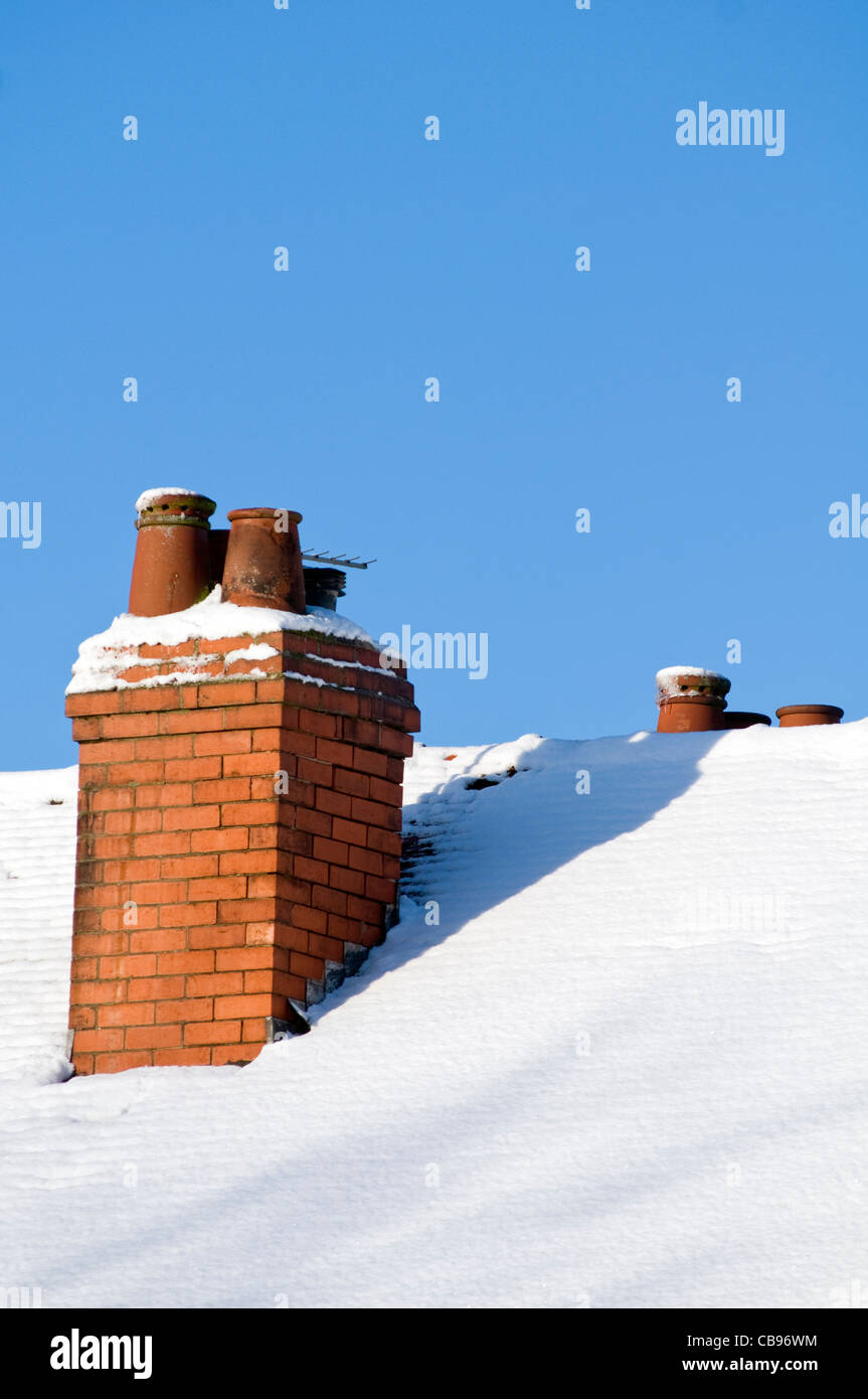 Une cheminée sur le toit couvert de neige d'une maison au Royaume-Uni Banque D'Images