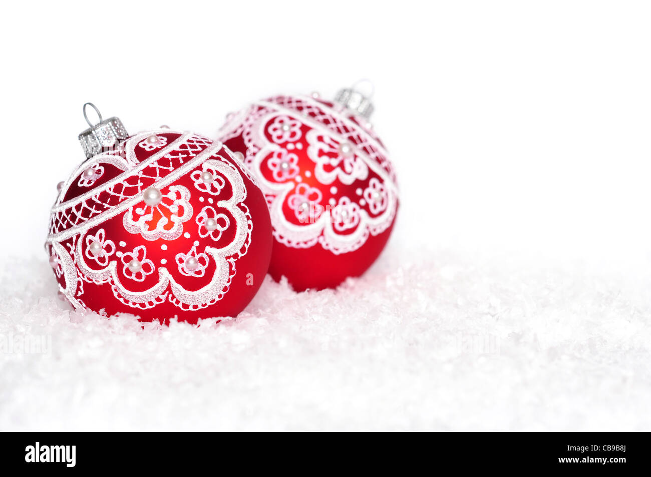 Boules de Noël rouge avec motif sur neige sur fond blanc Banque D'Images