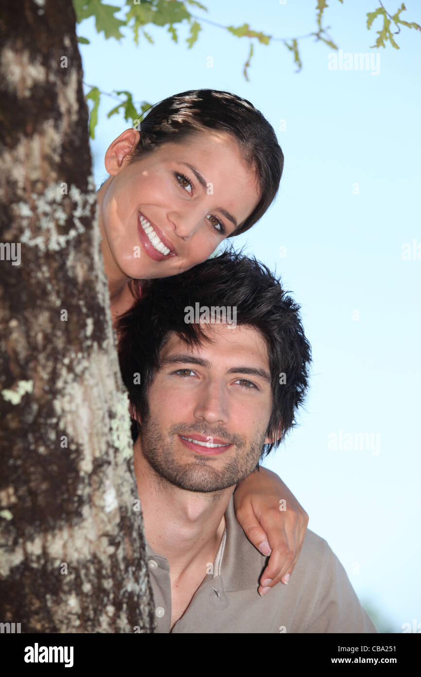 Couple se cacher derrière tree Banque D'Images