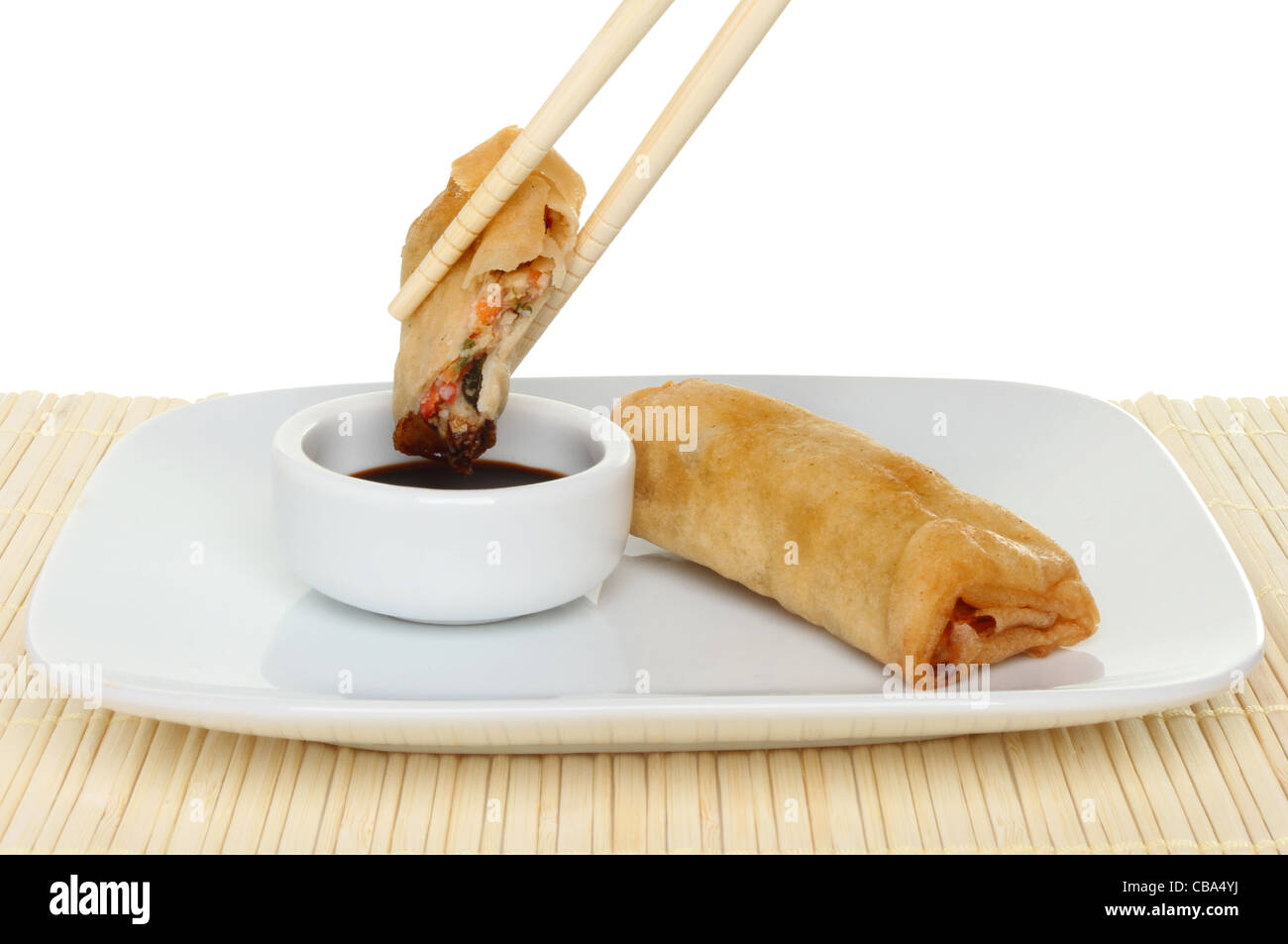 Crêpe en rouleau chinois baguettes trempés dans la sauce soja avec une bobine entière sur une plaque Banque D'Images