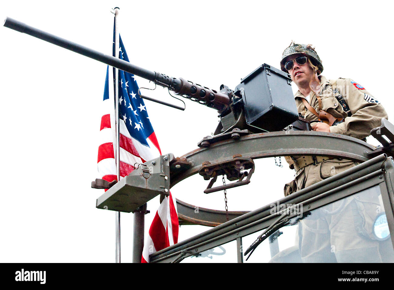 La reconstitution médiévale habillé en WWII GI américain mans une désactivée mitrailleuse montée sur une guerre préservé vintage US Army truck Banque D'Images