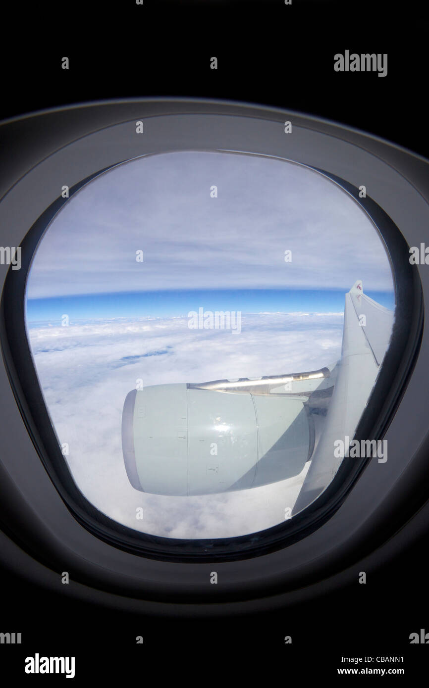 Vue à travers la fenêtre du passager jet avion de Qatar, aile Ciel et nuages Banque D'Images