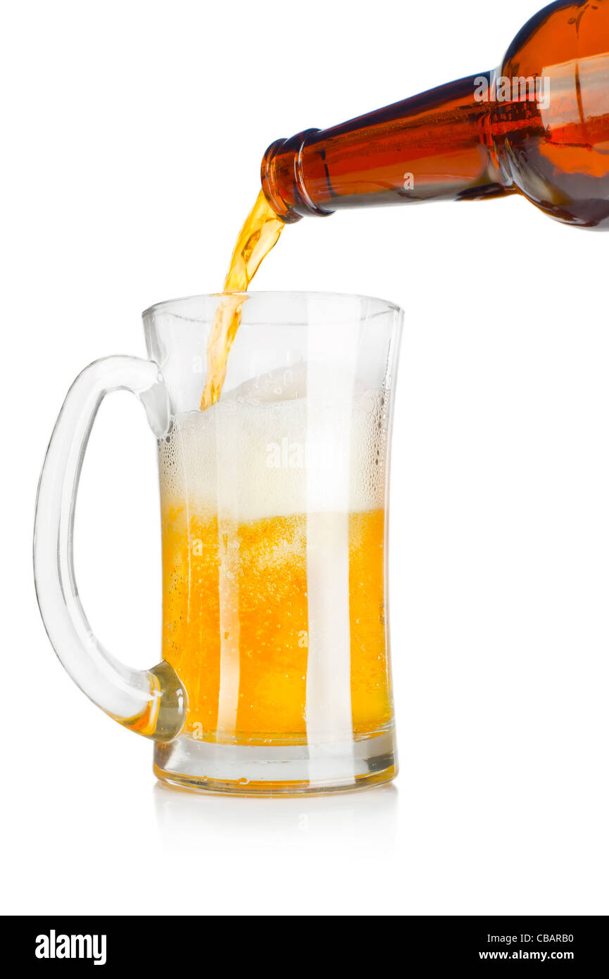 Verser la bière à partir de la bouteille en verre dans un mug sur fond blanc Banque D'Images