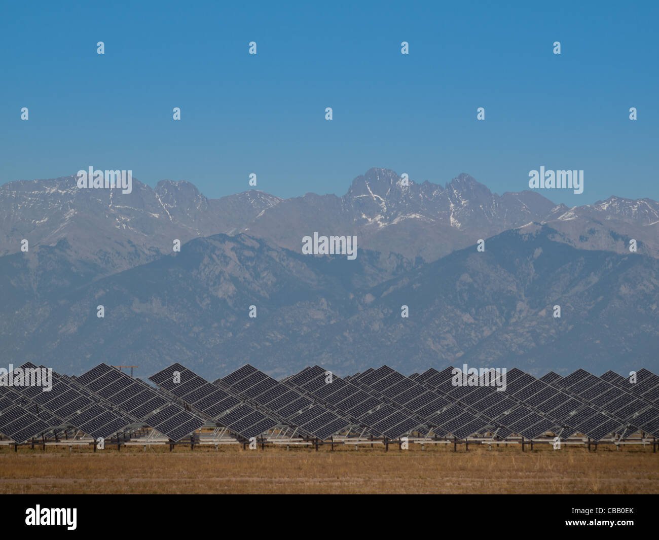 Une série de grands panneaux solaires forme une ligne symétrique à une centrale électrique dans la vallée de San Luis Colorado central. Ces panneaux utilisent un système de suivi pour suivre le soleil, la collecte de l'énergie et l'utilisation de cellules photovoltaïques pour transformer la lumière du soleil en électricité. Banque D'Images