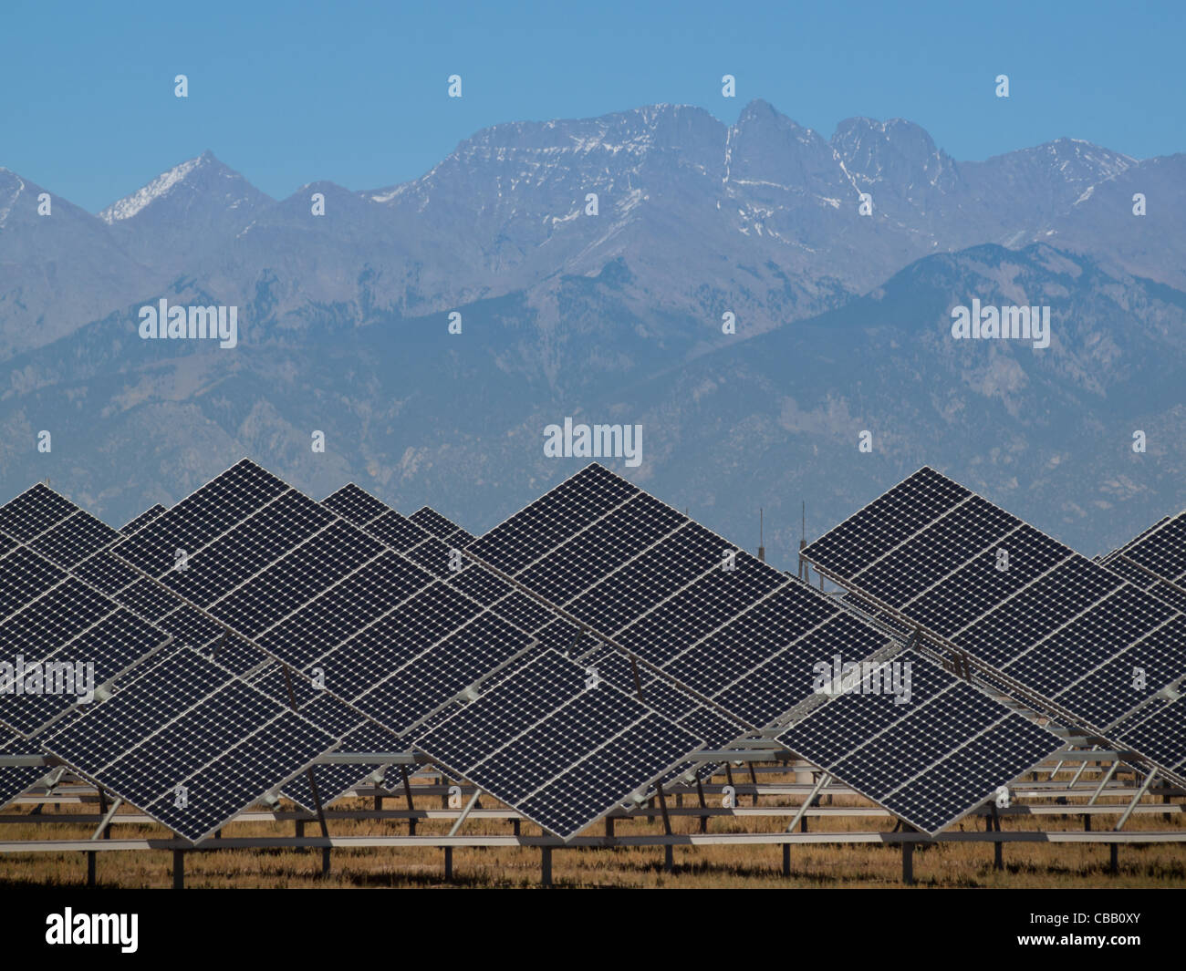 Une série de grands panneaux solaires forme une ligne symétrique à une centrale électrique dans la vallée de San Luis Colorado central. Ces panneaux utilisent un système de suivi pour suivre le soleil, la collecte de l'énergie et l'utilisation de cellules photovoltaïques pour transformer la lumière du soleil en électricité. Banque D'Images