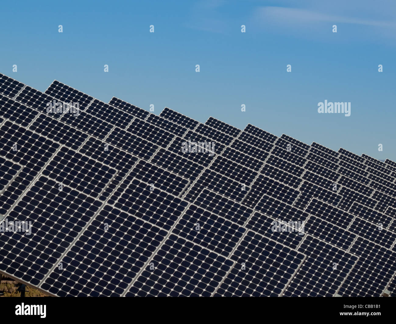 Une série de grands panneaux solaires forme une ligne symétrique à une centrale électrique dans la vallée de San Luis Colorado central. Ces panneaux utilisent un système de suivi pour suivre le soleil, la collecte de l'énergie et l'utilisation de cellules photovoltaïques pour transformer la lumière du soleil en électricité. Banque D'Images