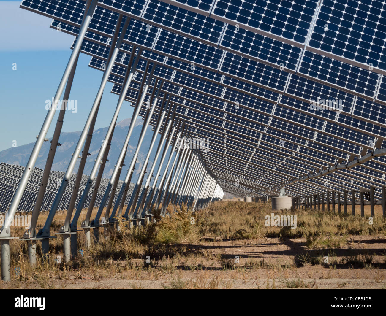 Une série de grands panneaux solaires forme une ligne symétrique à une centrale électrique dans la vallée de San Luis Colorado central. Ces panneaux utilisent un système de suivi pour suivre le soleil, la collecte de l'énergie et l'utilisation de cellules photovoltaïques pour transformer la lumière du soleil en électricité. Banque D'Images