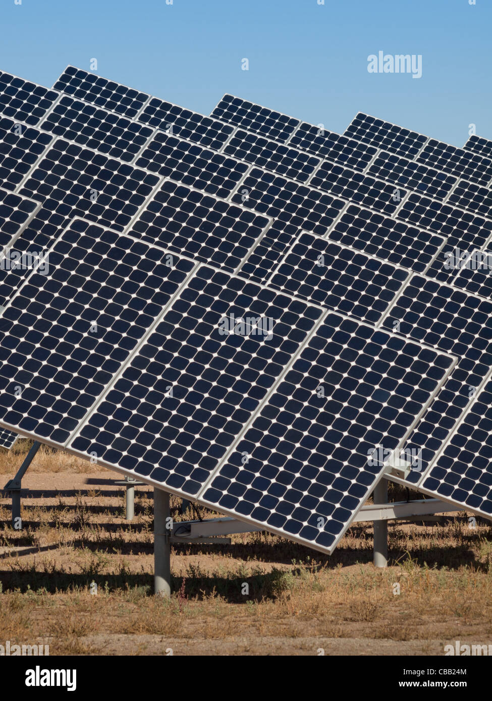 Une série de grands panneaux solaires forme une ligne symétrique à une centrale électrique dans la vallée de San Luis Colorado central. Ces panneaux utilisent un système de suivi pour suivre le soleil, la collecte de l'énergie et l'utilisation de cellules photovoltaïques pour transformer la lumière du soleil en électricité. Banque D'Images