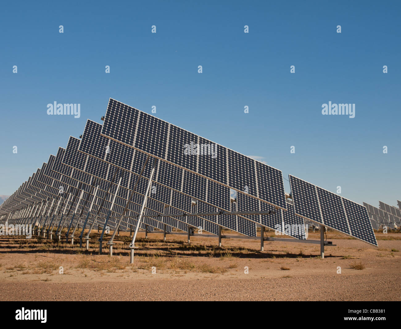 Une série de grands panneaux solaires forme une ligne symétrique à une centrale électrique dans la vallée de San Luis Colorado central. Ces panneaux utilisent un système de suivi pour suivre le soleil, la collecte de l'énergie et l'utilisation de cellules photovoltaïques pour transformer la lumière du soleil en électricité. Banque D'Images