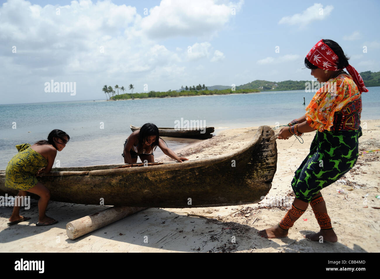 Guna femme indigène avec des enfants qui achigne un cayuco sur l'île de Corbisky à Guna Yala, Panama. Banque D'Images