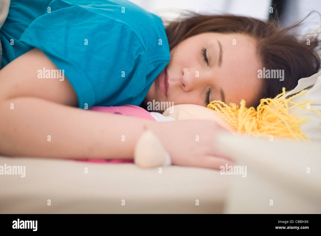 Teenage girl sleeping avec poupée de chiffon Banque D'Images