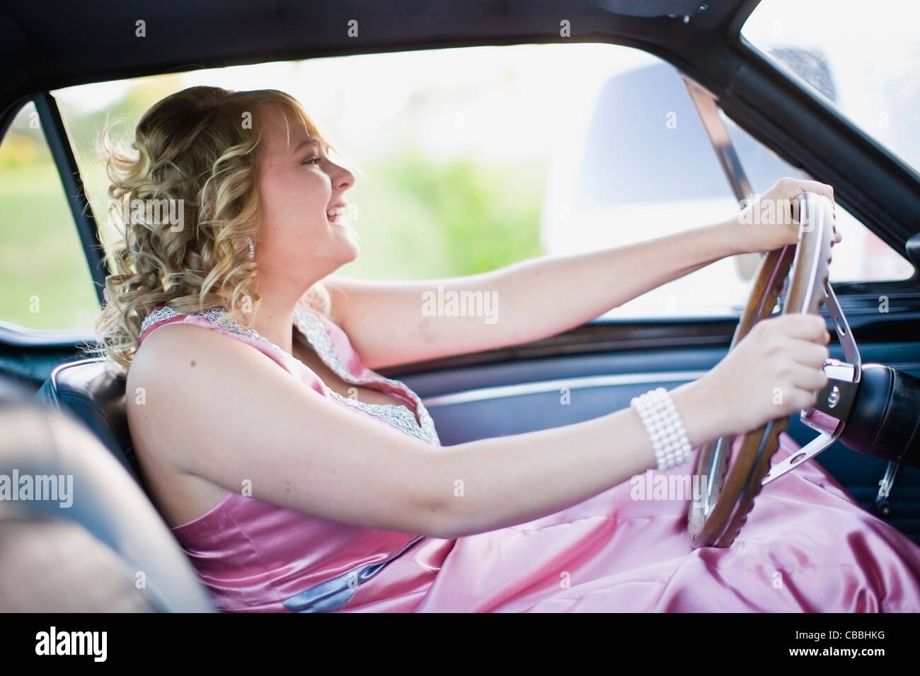 Teenage girl in gown driving car Banque D'Images