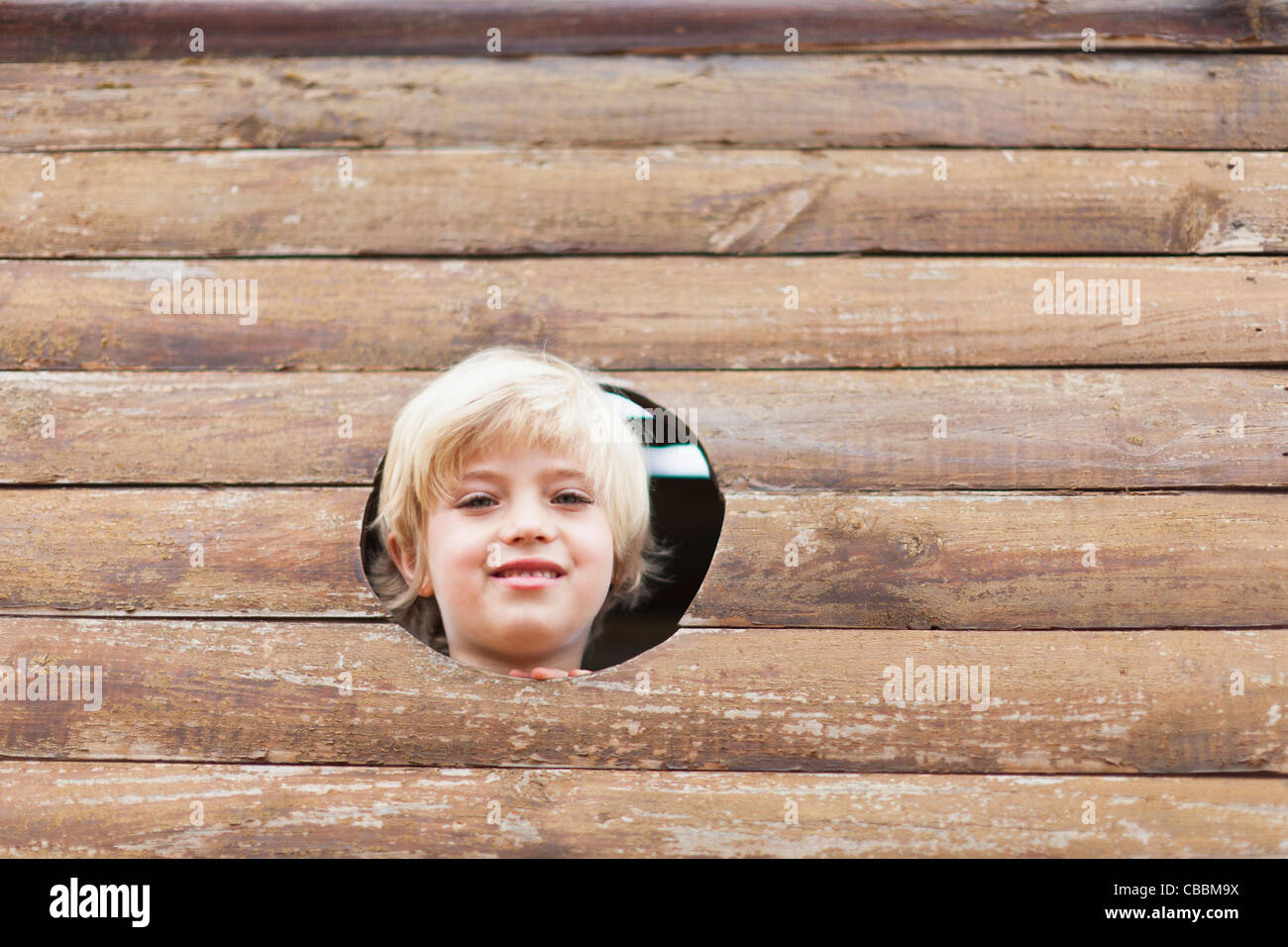 Boy peeking through hole dans playhouse Banque D'Images