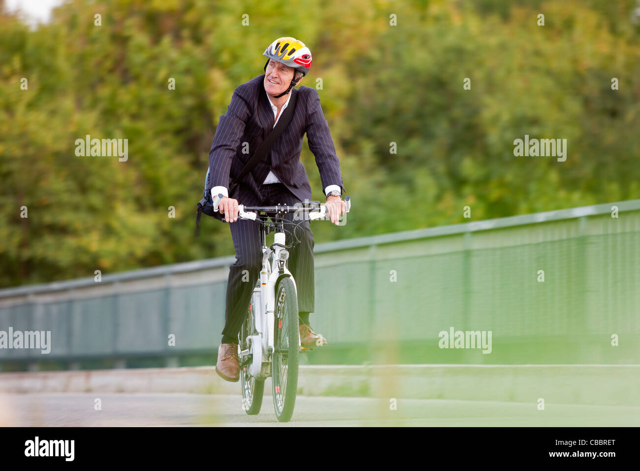 Businessman riding bicycle on bridge Banque D'Images