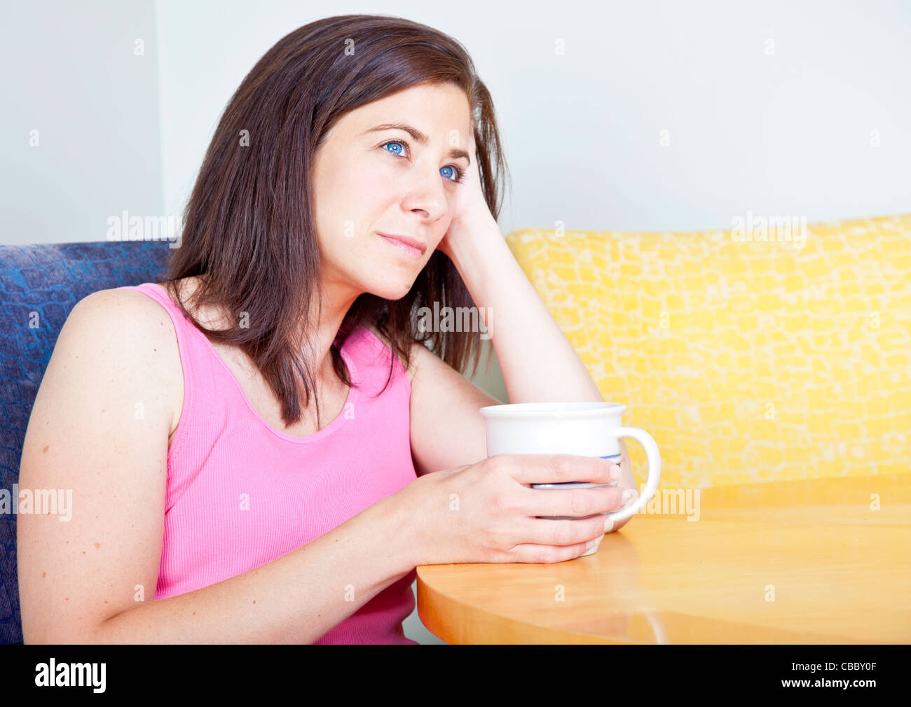 Woman sitting at table boire du café seul Banque D'Images
