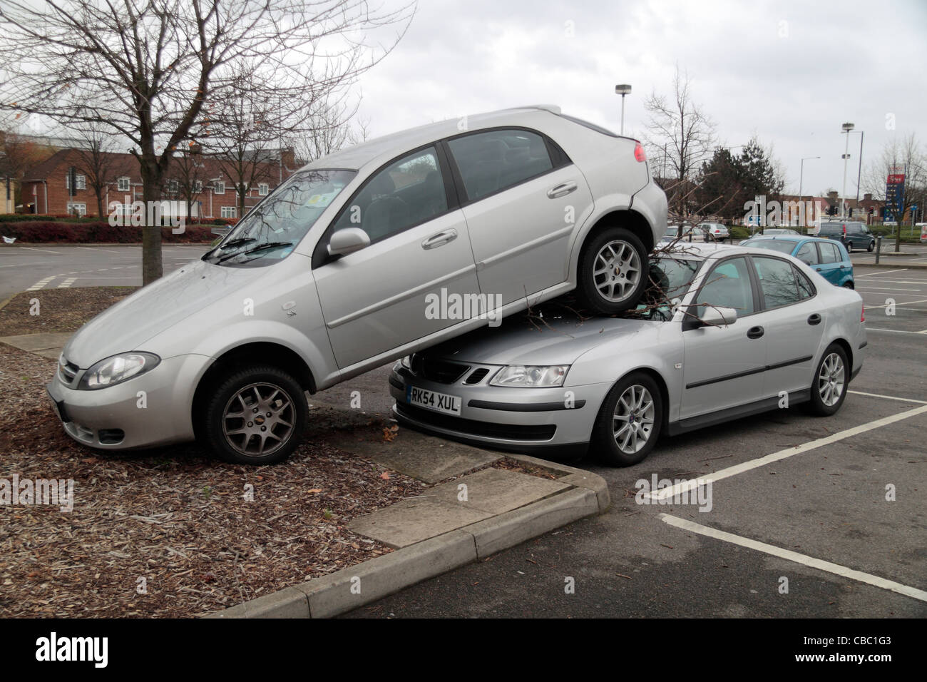 Parking un incident où une voiture a été accidentellement renversé un trottoir, dans un arbre et sur le capot d'une autre voiture. Banque D'Images