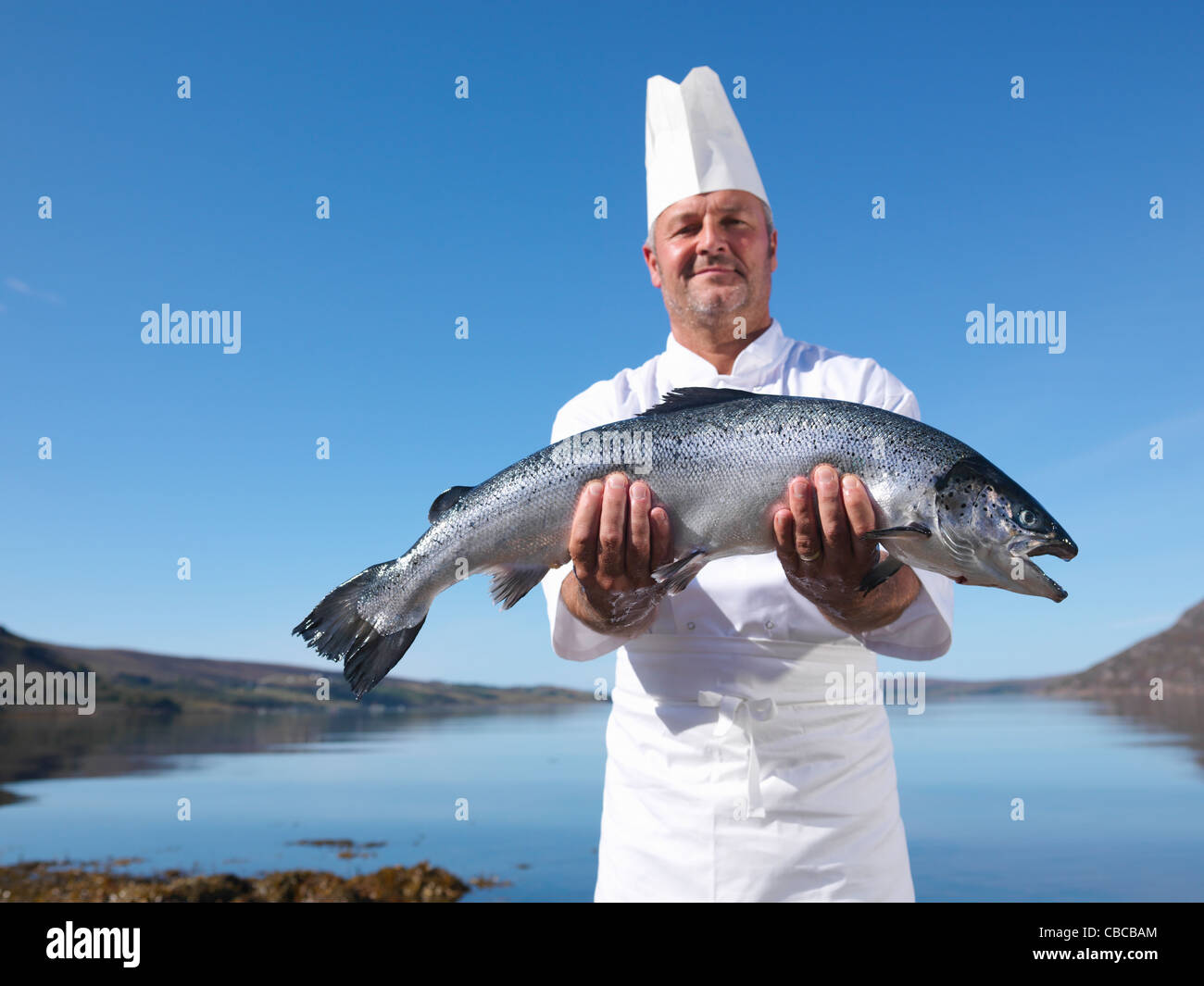 Chef holding salmon by lake Banque D'Images