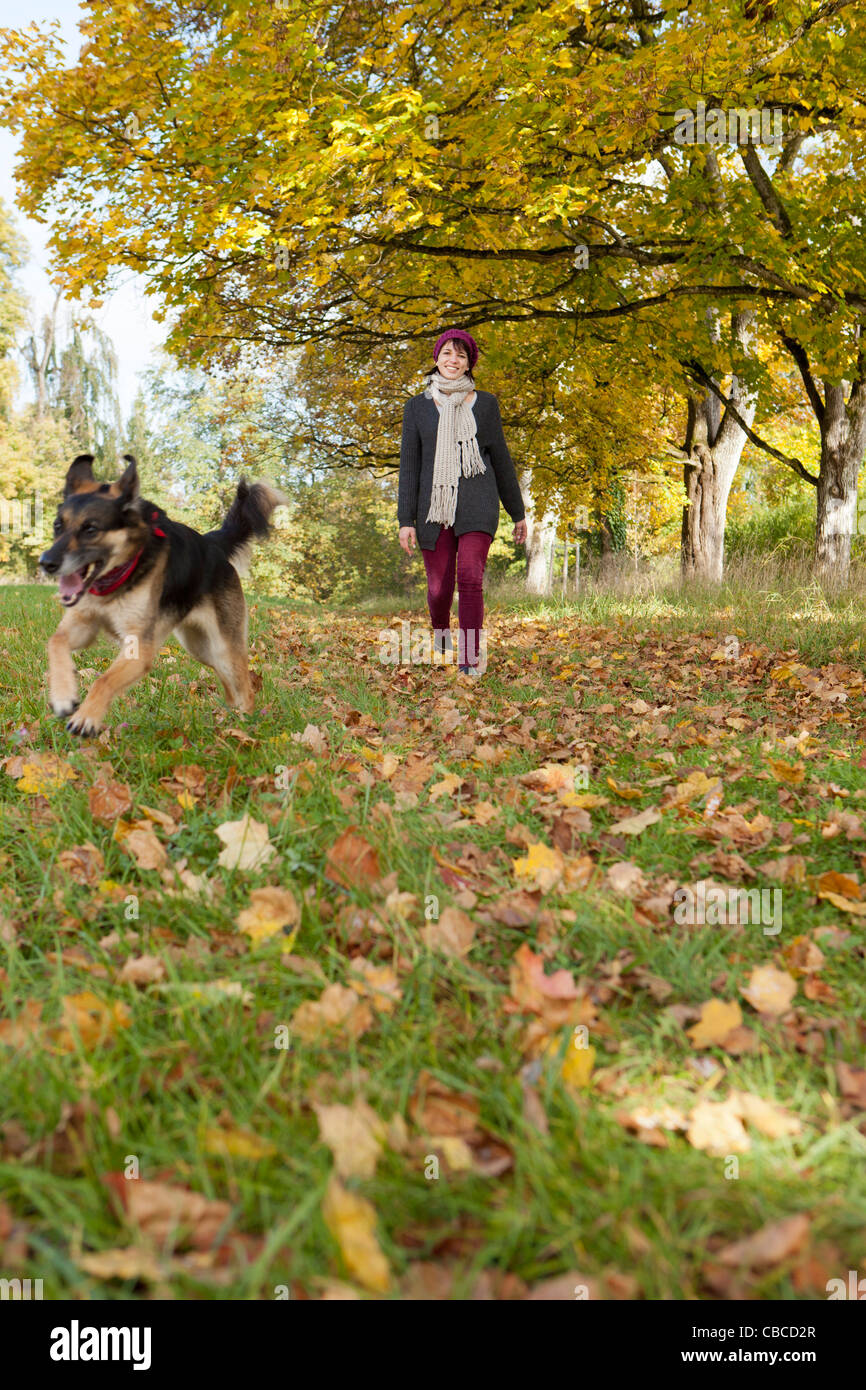 Smiling woman walking dog in park Banque D'Images