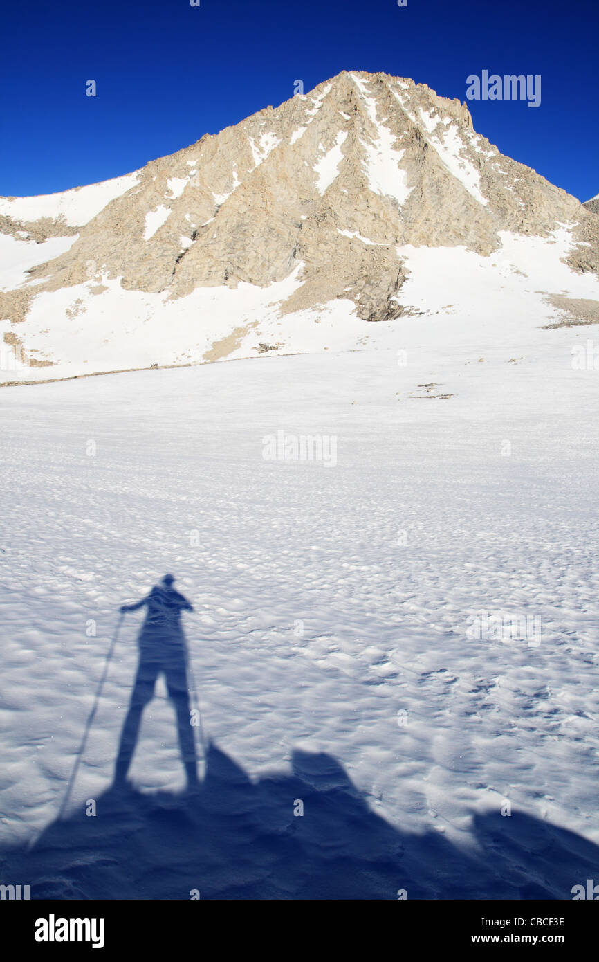 L'ombre de l'homme de randonnée sur la neige et le Mont Merriam dans les montagnes de la Sierra Nevada de Californie Banque D'Images