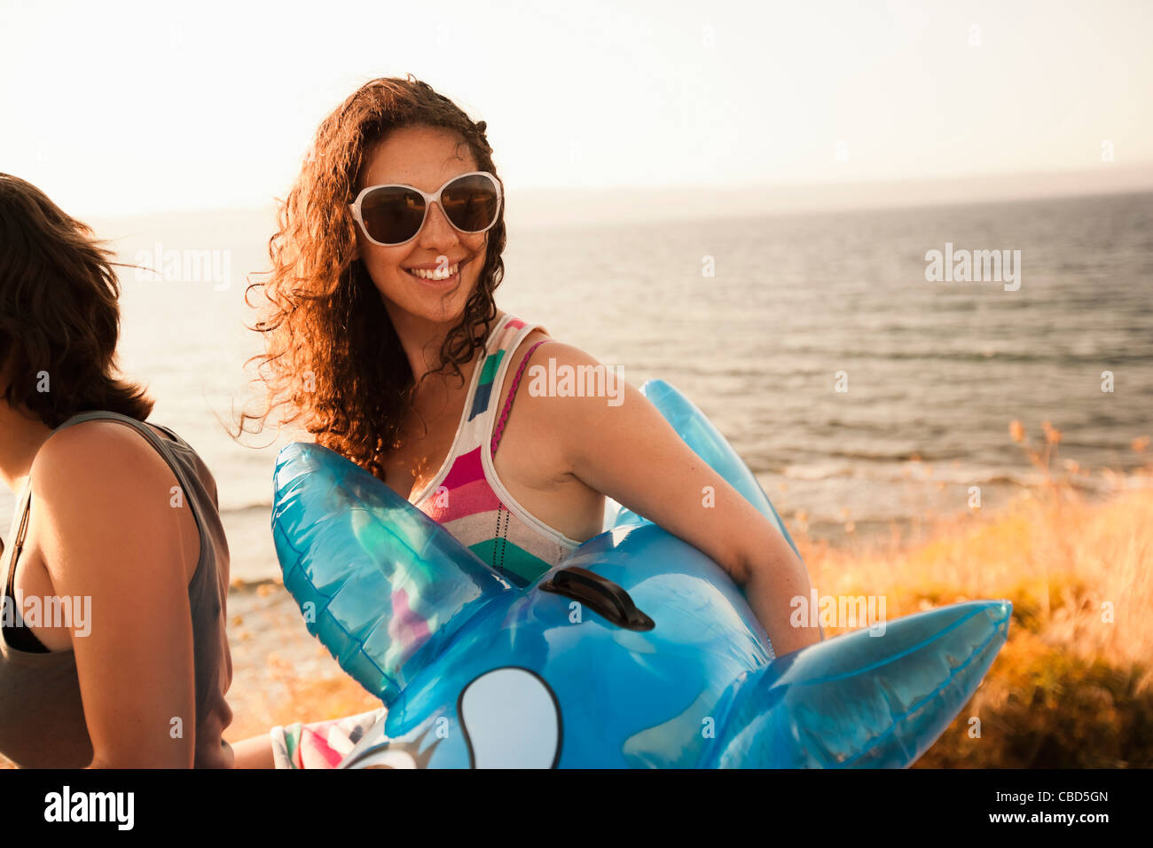 Femme transportant inflatable toy on beach Banque D'Images