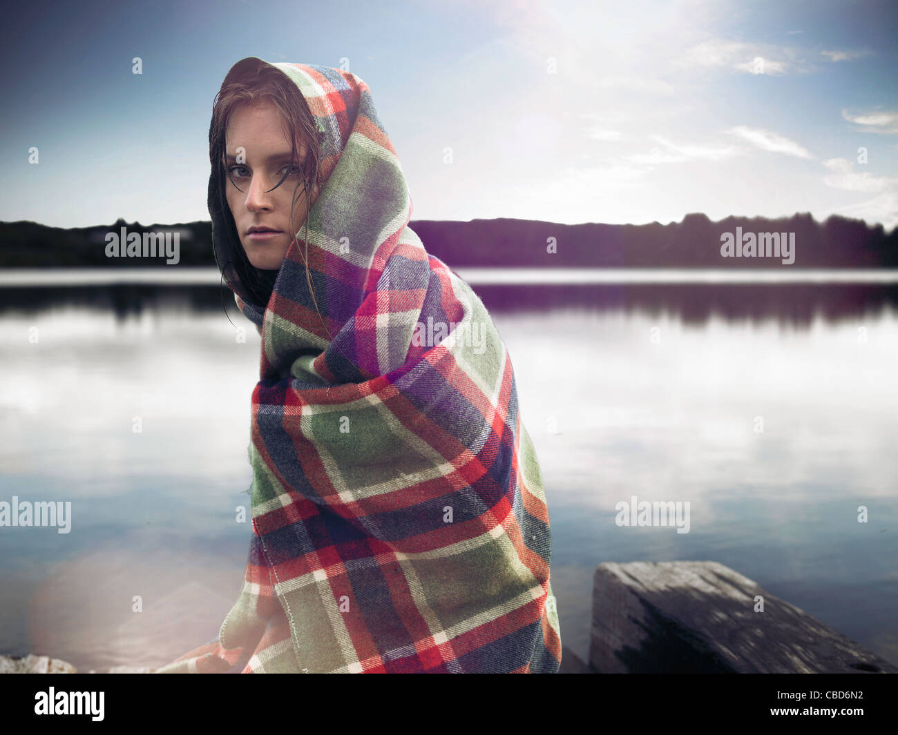 Femme en couverture sur dock en lake Banque D'Images