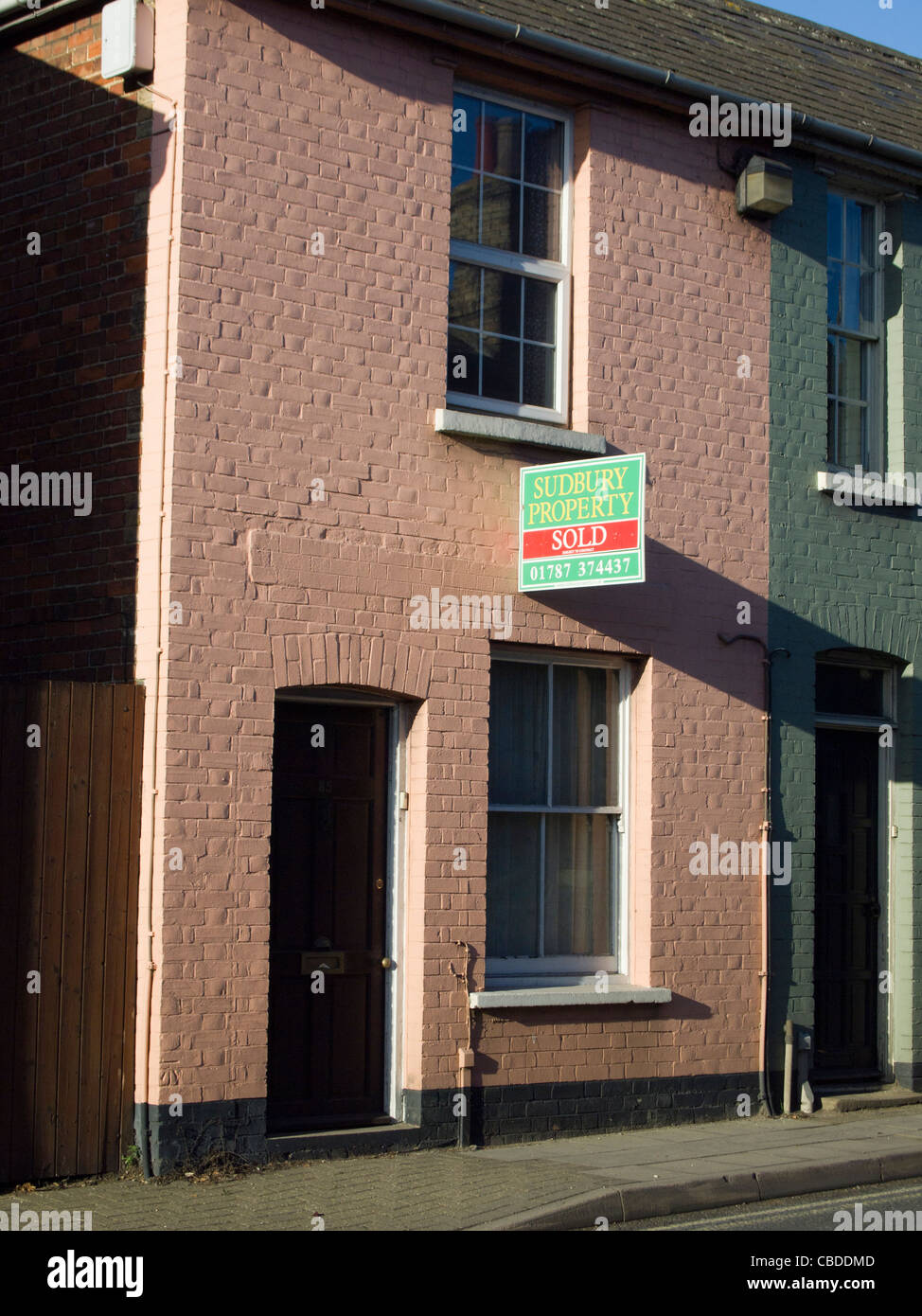 Une petite propriété mitoyenne sans jardin, avec un signe sur l'VENDU peint rose mur avant. Banque D'Images
