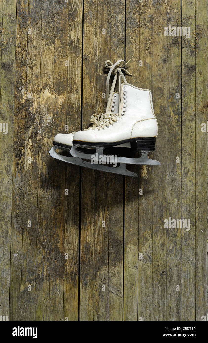 Patins à glace blanc accroché sur un vieux mur en bois patiné Banque D'Images