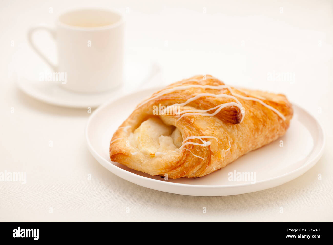 Pâtisserie croissant apple sur plaque blanche avec une tasse de café espresso en arrière-plan Banque D'Images