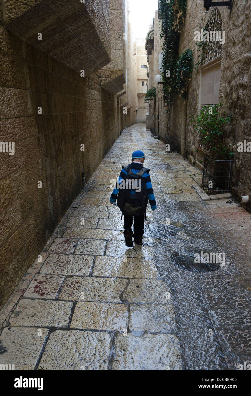 Garçon de marcher sous la pluie dans les rues du quartier juif de la vieille ville de Jérusalem. Israël. Banque D'Images