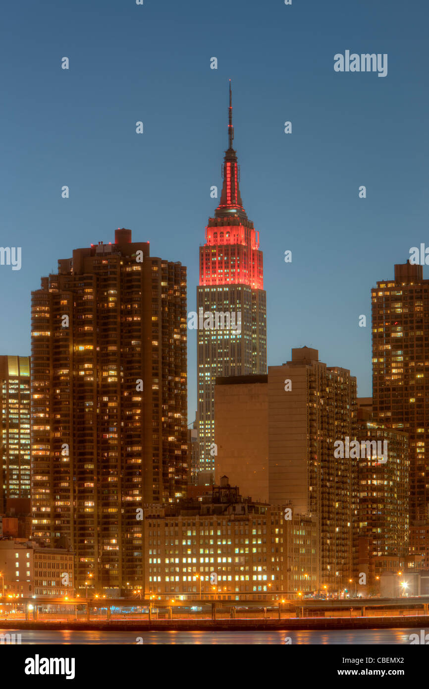 L'Empire State Building, allumé en rouge pour la Journée mondiale contre le sida, et d'autres bâtiments sur le côté est, au crépuscule de la ville de New York. Banque D'Images