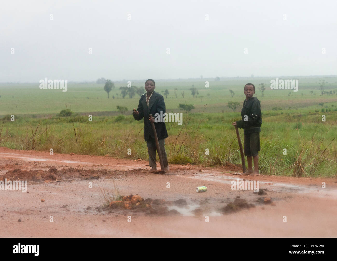 Les garçons de remplir à nouveau les trous sur la route, Bie, Angola Banque D'Images